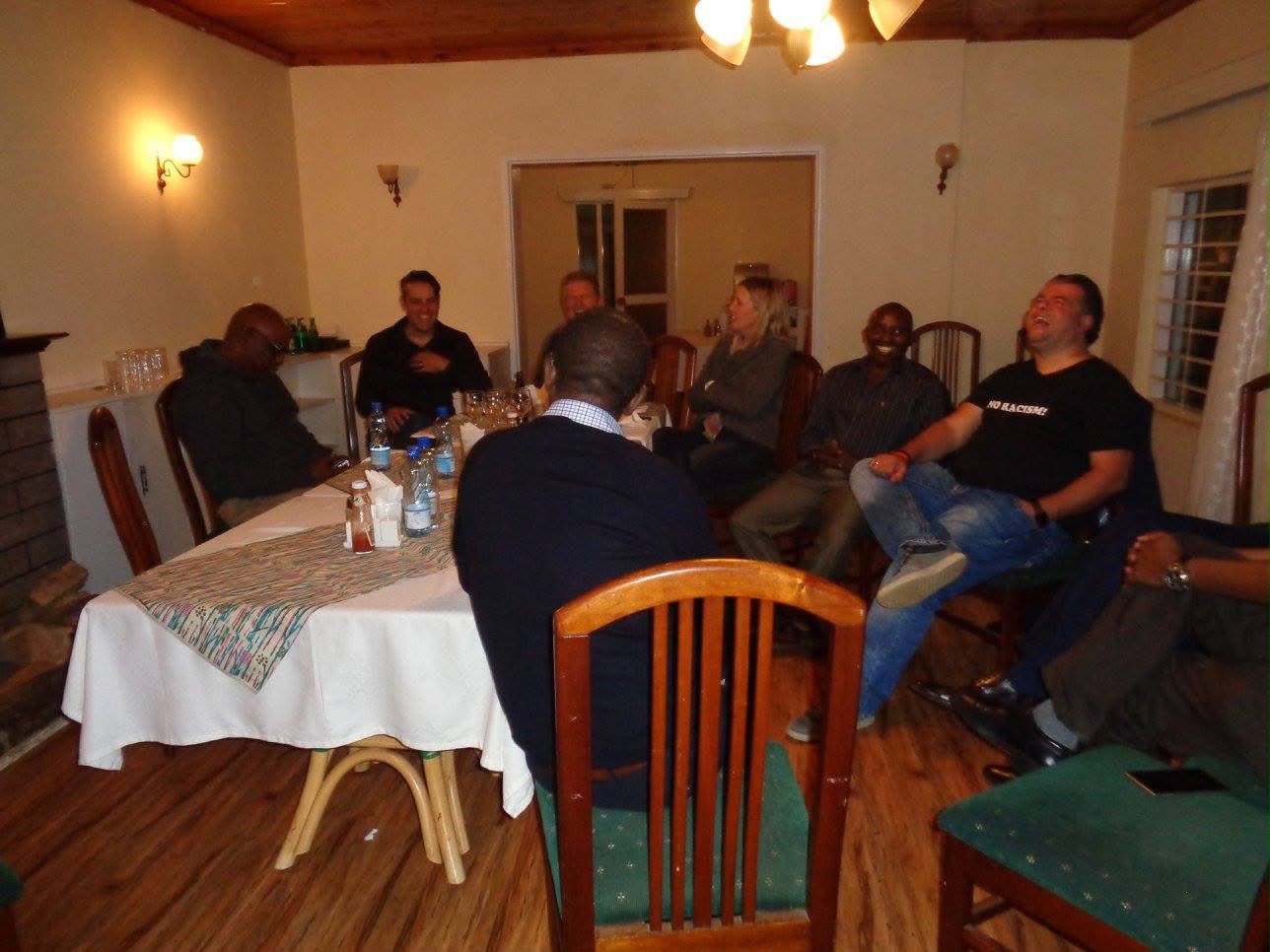 Founders sit around a dining table in warm evening light at Thayu resort, talking and laughing together during the September 2016 SPEC founding retreat.