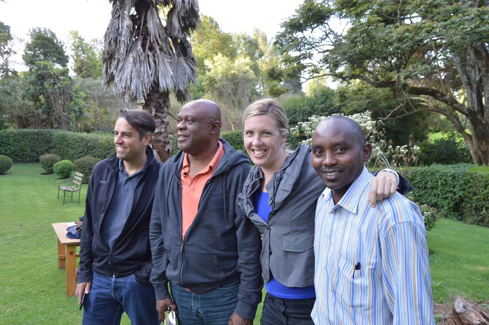 Four founding members, three men and one woman, stand together smiling in the gardens at Thayu resort in Limuru during the September 2016 SPEC gathering.